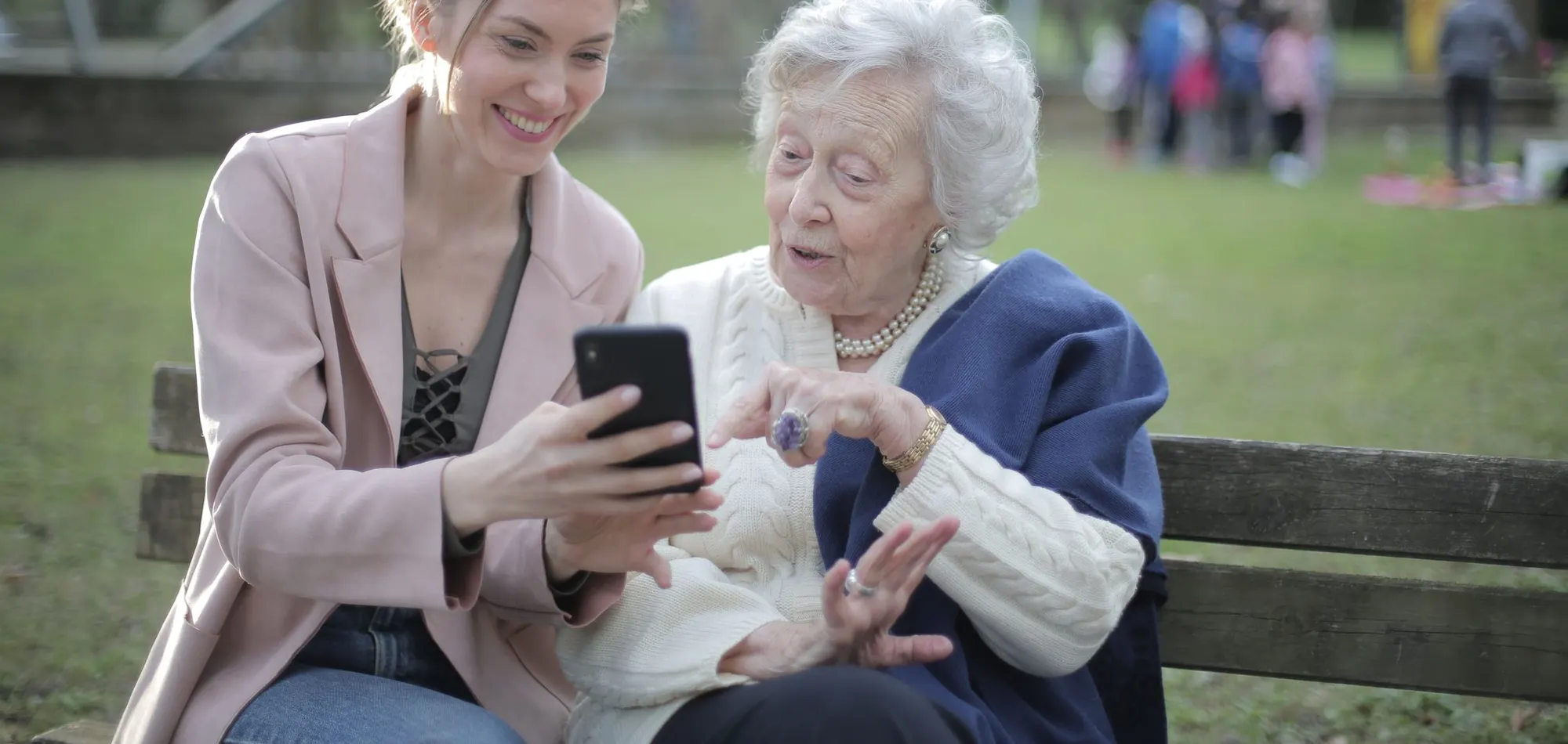 Grossmutter und Enkelin schauen gemeinsam lächelnd auf ein Smartphone